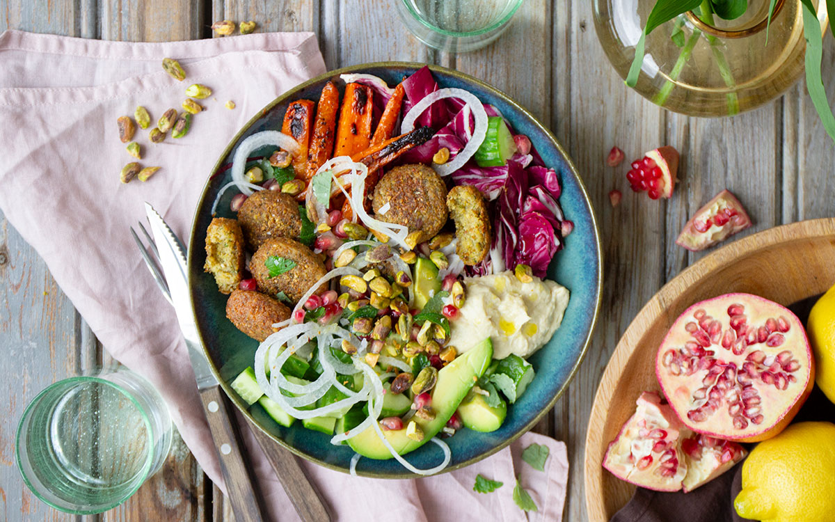 Bowl med anammas falafel, hummus, harissarostade morötter, granatäpplekärnor, silverlök, avokado och pistagenötter.