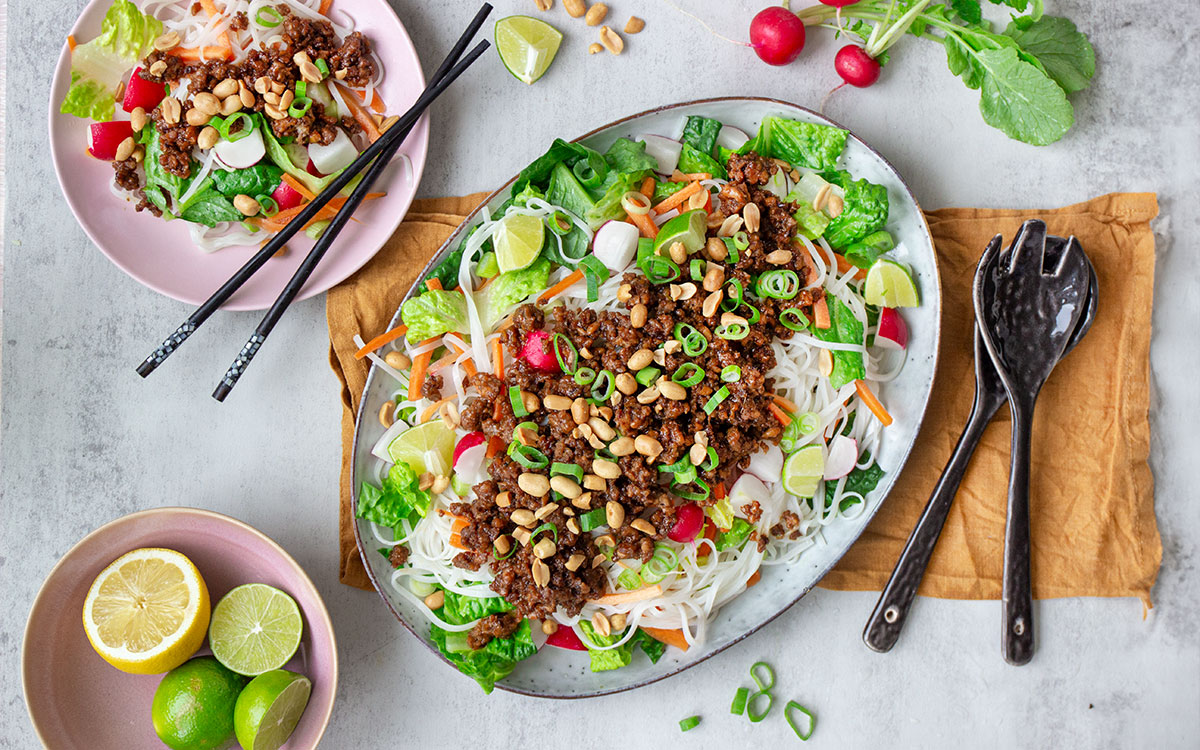 Fat med asiatisk nudelsallad med grönsaker, vegetarisk hoisinfärs och hackade jordnötter.